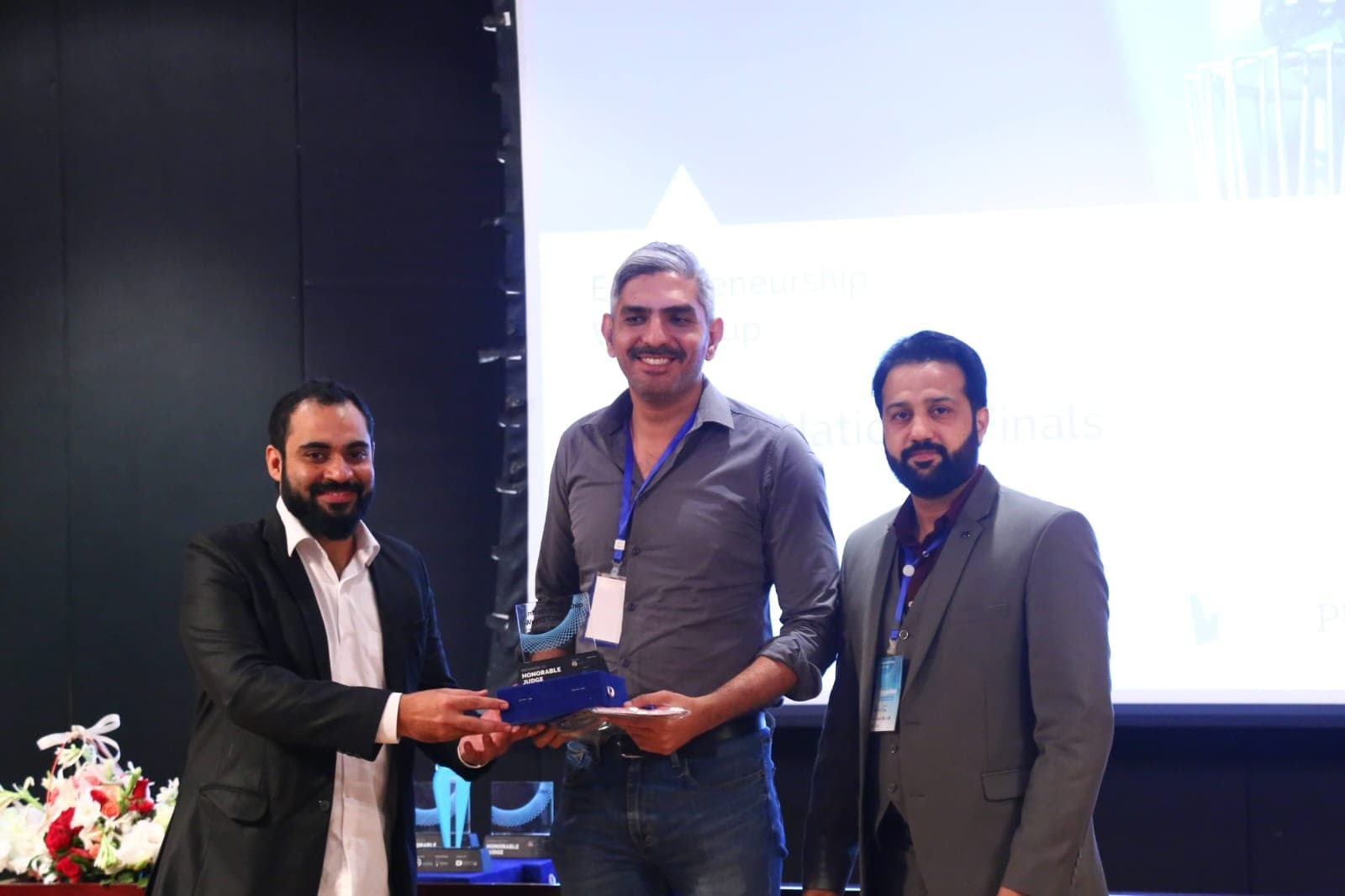 Ali Ahmed presenting an Honorable Judge award on stage at the Entrepreneurship World Cup Pakistan National Finals