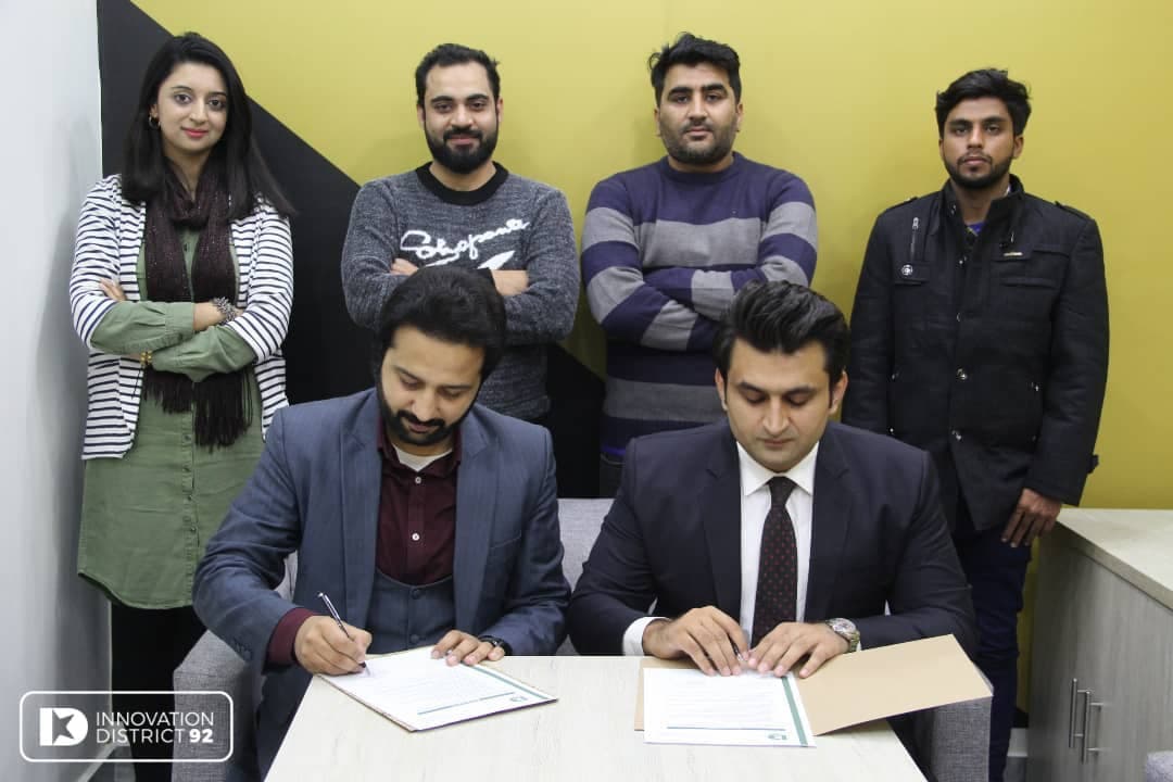 A partnership agreement being signed at Innovation District 92, with the team witnessing